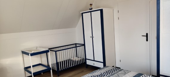 Großes Schlafzimmer mit Kinderbett und Pflegetisch